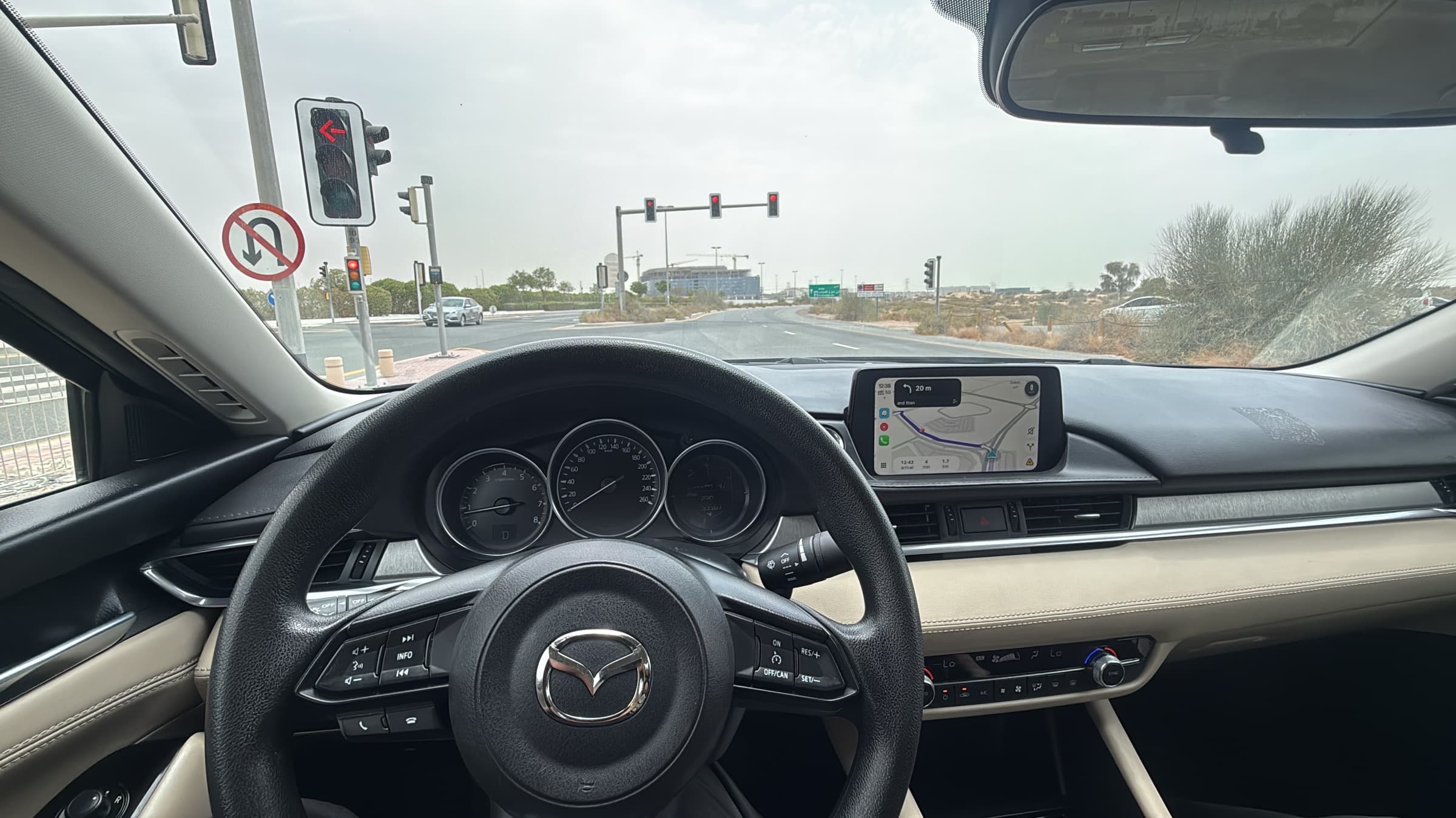 Driver's view from behind the wheel at a Dubai junction, with traffic lights and a no U-turn sign ahead