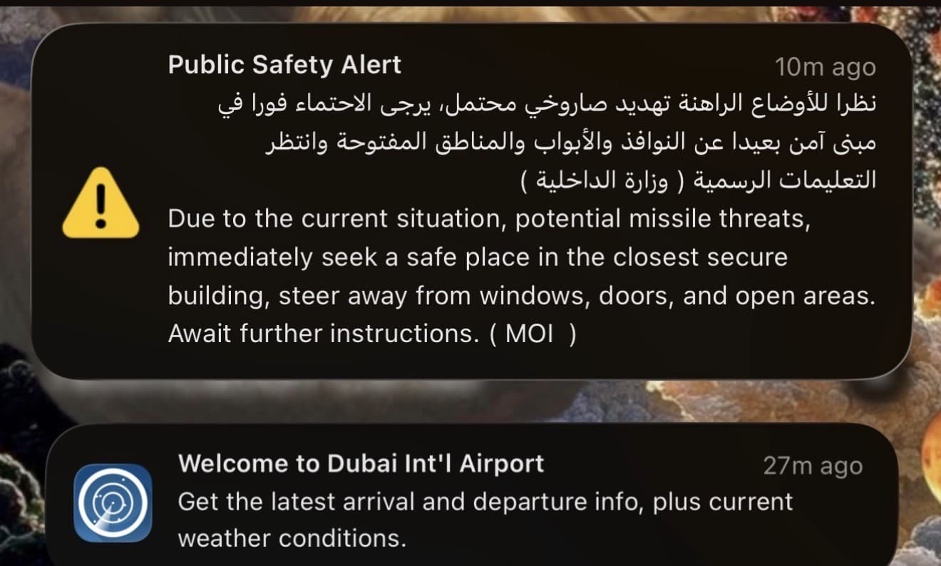 A UAE Ministry of Interior public safety alert on a phone lock screen warning of potential missile threats and advising people to seek a secure building